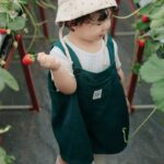 Cute child holding a strawberry in a Vietnamese greenhouse, showcasing agriculture and freshness.